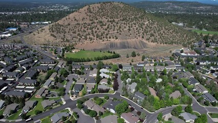 Small town neighborhood around large hill in Bend, Oregon. Rising drone shot.