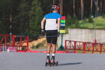 Athletes ride roller skis on asphalt track, group of ski rollers in helmet, cross-country skiing with roller ski in summer sunny day, sportsmen ski-rollers riding, biathlete training 