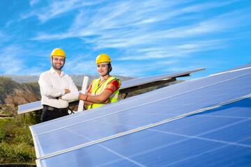 Portrait of Young indian woman technicians standing near solar panels against blue sky.Industrial workers solar system installation, alternative renewable green energy generation concept.