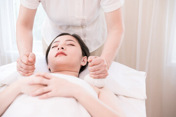 Fototapeta na wymiar Young Asian woman getting spa massage with Thai Herbal Ball Hot Compress massage at beauty spa salon. Relaxing massage for health