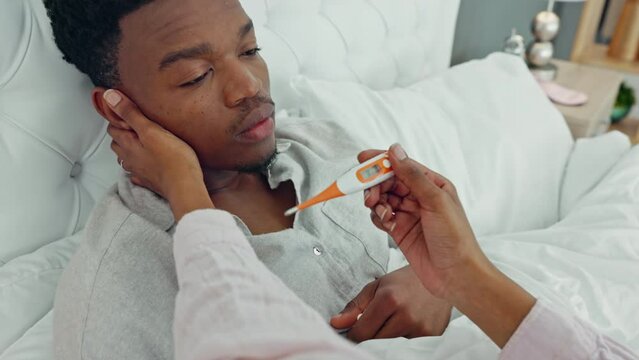 Girlfriend, health and covid sick man with thermometer test for flu, cold and body temperature in bed at home. Headache, fever and sad male with health, virus and fatigue with woman nurse in bedroom