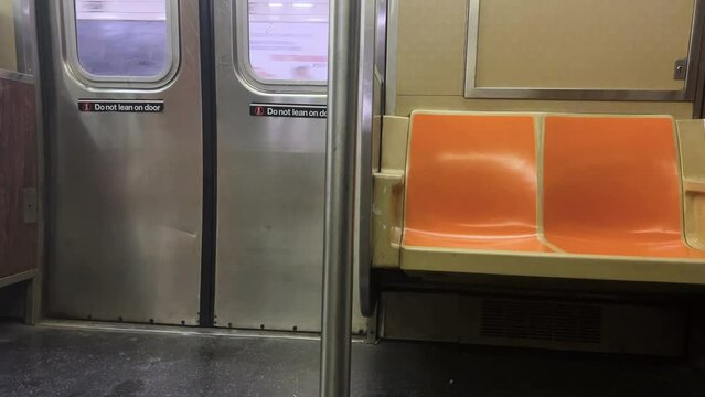 footage from inside an empty NYC subway car with sliding doors and empty seats