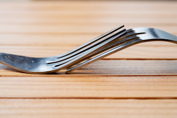 A pair of steel forks on a wooden table. macro shot