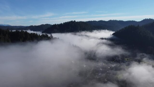 Flying over the clouds surrounding rolling hills.