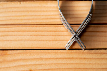A pair of steel forks on a wooden table. macro shot