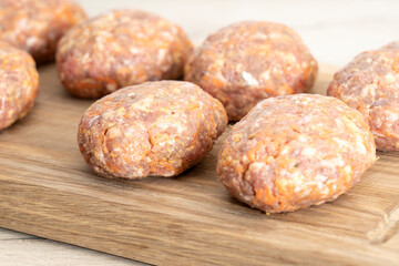 raw homemade meatballs on a massive board made of natural wood