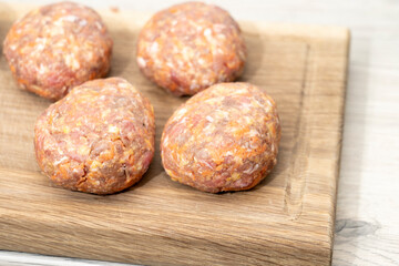 raw homemade meatballs on a massive board made of natural wood