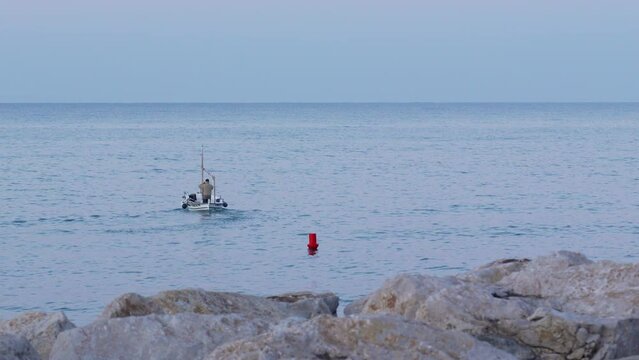 lone fisherman's boat departs at sea during early morning light
