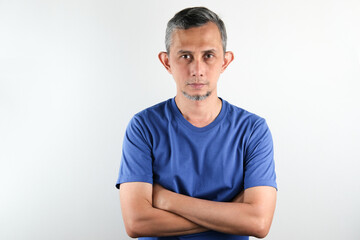 Fototapeta premium Asian man wearing blue tshirt over isolated white background serious face with crossed arms looking at the camera. Positive person. 