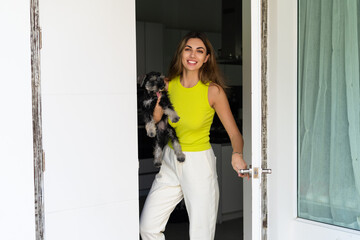 Welcome. Portrait of cheerful woman standing in doorway of modern apartment, greeting visitor and...