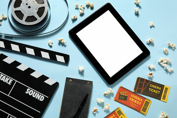 Movie clapper with reel, popcorn, tablet computer, tickets and popcorn on blue background