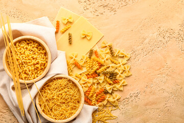 Composition with bowls of different types of raw pasta on color background