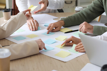 Group of people with sticky notes working on business plan at table in office, closeup - obrazy, fototapety, plakaty