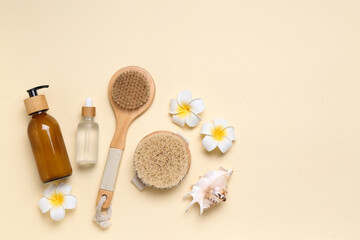Composition with massage brushes, bottles of cosmetic products and flowers on color background