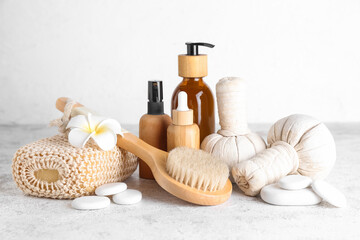 Bath supplies and bottles of cosmetic products on light background