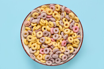 Bowl of colorful cereal rings on blue background