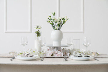 Beautiful table setting for International Women's Day celebration with eustoma and orchid flowers in light room