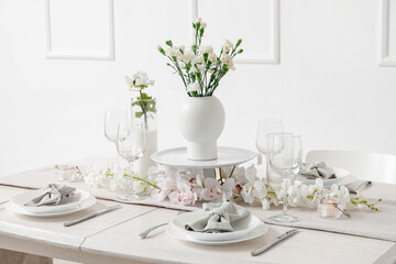 Beautiful table setting for International Women's Day celebration with eustoma and orchid flowers in light room