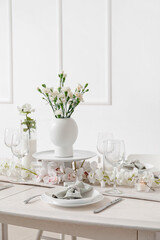 Beautiful table setting for International Women's Day celebration with eustoma and orchid flowers in light room