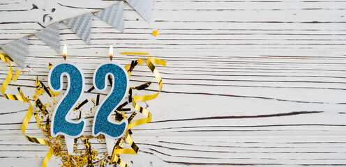 Number 22 blue celebration candle on white wooden background. Happy birthday candles. Concept of...
