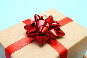 Gift box with red bow on blue background, closeup