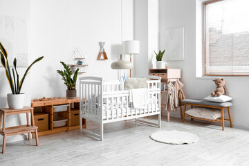 Interior of light children's bedroom with baby crib, table and bench