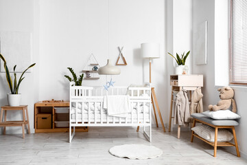 Interior of light children's bedroom with baby crib, table and bench