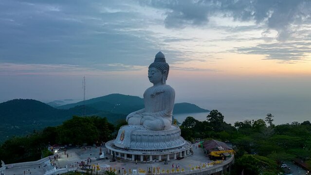 aerial hyper lapse view Phuket big Buddha in beautiful sunset..the sun shines through the clouds impact on ocean surface.The beauty of the statue fits perfectly with the charming nature.