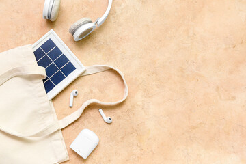 Composition with portable solar panel and wireless earphones on beige grunge background