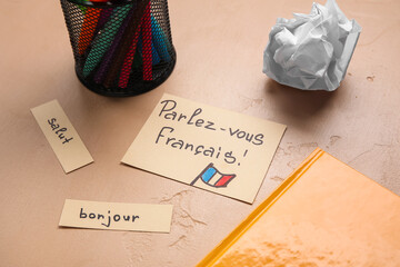 Papers with French words and stationery on beige background, closeup