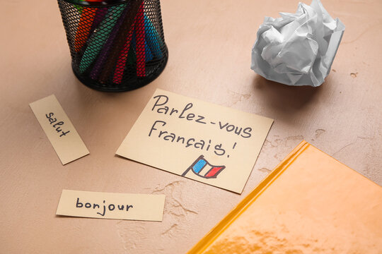 Papers with French words and stationery on beige background, closeup