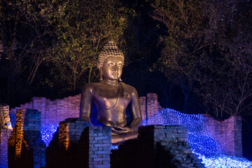 Obraz premium bronze buddha statue at night NaSatta Thai Park located Wang Yen Subdistrict, Ratchaburi, Thailand