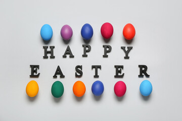 Painted eggs and text HAPPY EASTER on grey background