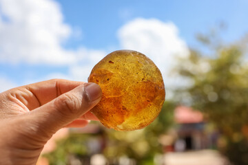 Close up view of clear Orange healing crystal held with hand against against sky