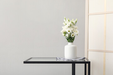 Vase with beautiful eustoma flowers on table in room