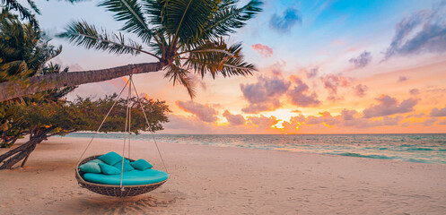 Romantic beach sunset. Palm tree with swing hanging before majestic clouds sky. Dream nature...