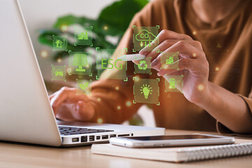 Businesswoman use a computer to analyze ESG, surrounded by ESG icons close to the computer screen in business investment strategy concept. environment social governance investment business concept.