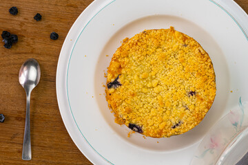Top view of delicious  homemade blueberry crumble cheesecake in white ceramic plate.