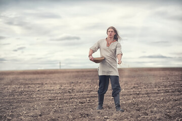 A young peasant sows the field with grain
