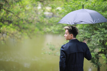 Spring rainy weather and a young man with an umbrella