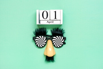 funny face - fake eyeglasses, nose and mustache, calendar date 01 April on green background Happy...