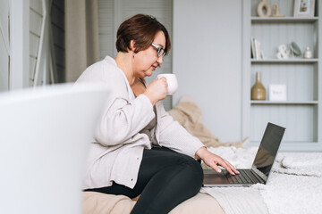 Smiling middle aged plus size woman working on laptop from home
