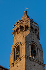 Obraz premium The top of the bell tower of the parish church of San Verano while the bells are ringing, against the blue sky, Peccioli, Pisa, Italy