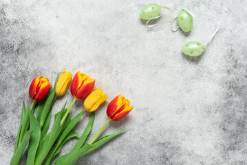 Tulips and decorative Easter eggs on a rustic background. Top view, flat lay. Happy easter