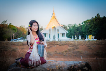 Beautiful thai girl of asian descent is sitting and looking to the copy space while holding a...