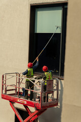 workers cleaning exterior window in a cage