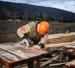 Carpenter using circular saw for cutting wooden truss. Man worker building wooden frame house. Carpentry concept.