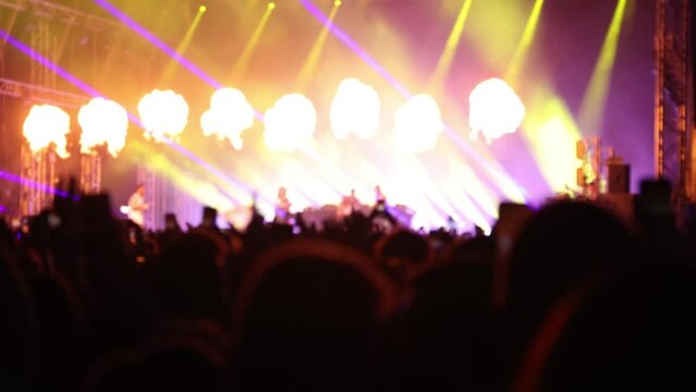 Concert stage illuminated by neon flashing lights and flames, band playing music