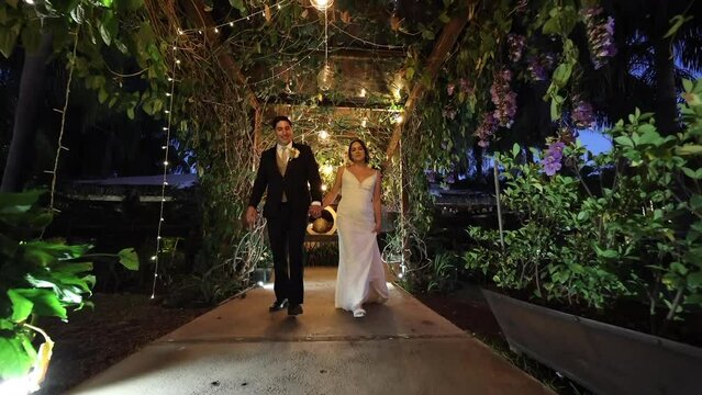 Low angle view of romantic couple looking happy. Man and woman walking with hand in hand to celebrate their wedding day with guests. High quality FullHD footage