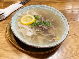 Pho Bo traditional Soup with beef, rice noodles, ginger, lime, chili pepper in bowl
